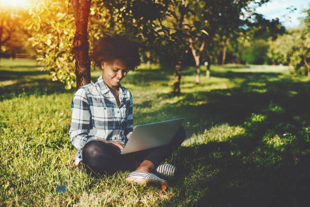 istock Curly black girl with laptop in park 668888838