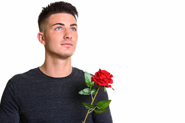 istock Close up of young handsome man thinking while holding red rose 668895760