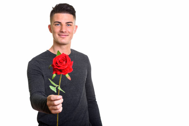 Studio shot of happy handsome man smiling while giving red rose horizontal shot