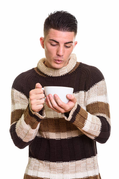 istock Young handsome man holding and blowing on coffee cup 668895938