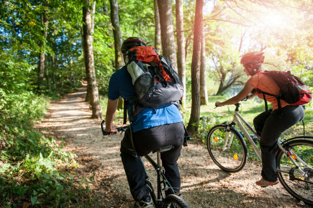 Kiev, Ukraine - October 15, 2017: Two mountain bikers resting after riding. Sportsmen with their bicycles standing in green summer forest. Sport activity, recreation, holiday leisure concept.