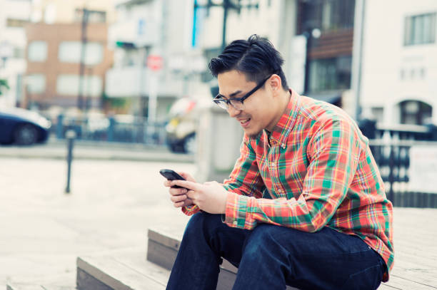 istock Young adult man using a smart phone in city 668933702