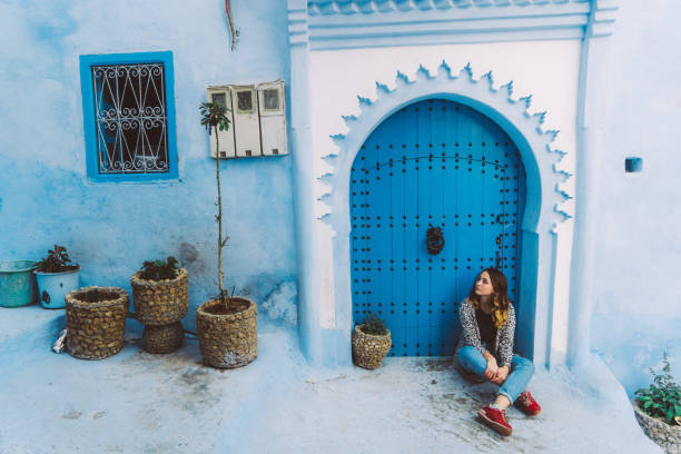 Woman sitting near the doors in Chefchaouen Young Caucasian woman sitting near the doors in Chefchaouen, Morocco chefchaouen stock pictures, royalty-free photos & images