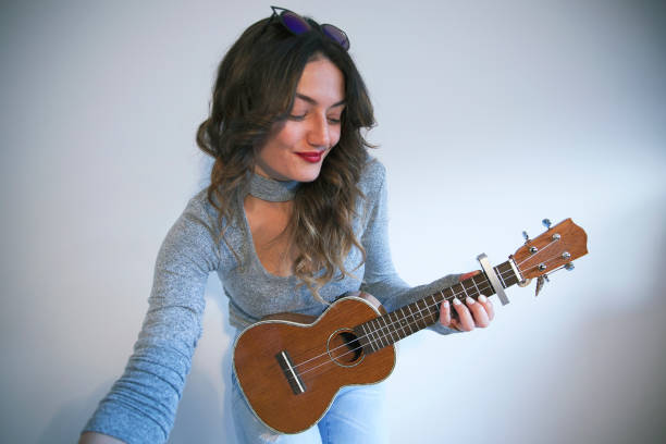 istock Beautiful young woman playing ukulele 668944678