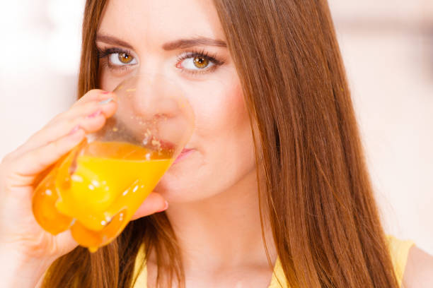istock Woman in kitchen drinking fresh orange juice 668947580