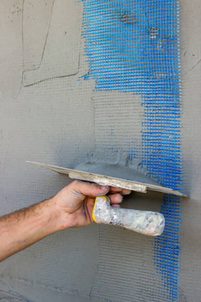 istock Facade plaster hand smoothing out wall with trowel 668947974