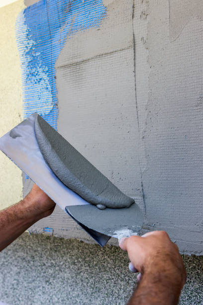 istock Facade plaster hand smoothing out wall with trowel 2 668951518