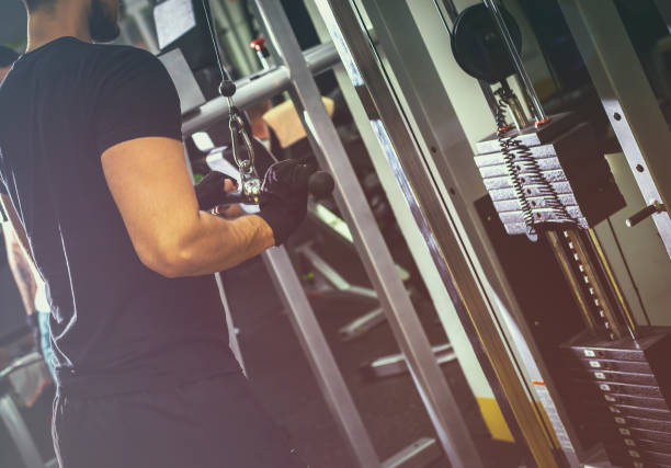 istock Man bodybuilder working out at the gym performing rope pushdown exercise on his triceps 668961546