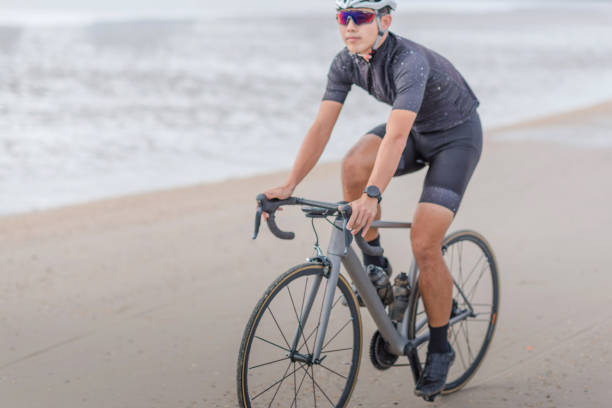 istock Young asian cyclist man ride  bicycle  the beach at the sunset 668965430