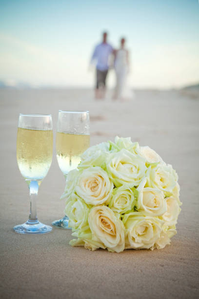 istock Rose Bouquet on a Sandy Beach with Bride and Groom in the background 668989996