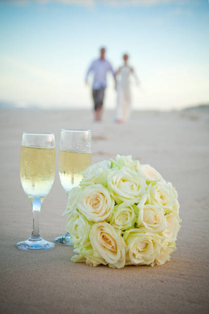istock Rose Bouquet on a Sandy Beach with Bride and Groom in the background 668990004