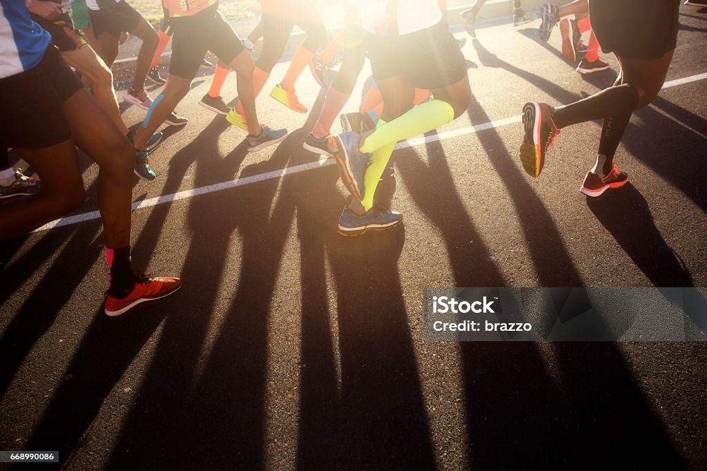 Piernas de los corredores de carretera con sombra en barra - Foto de stock de Maratón libre de derechos