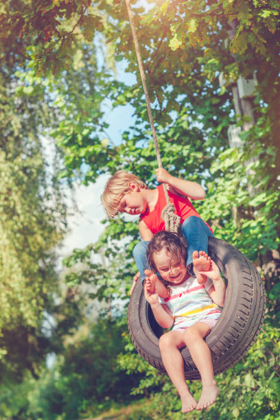 pequeño niño y niña en verano - child swing swinging spring fotografías e imágenes de stock