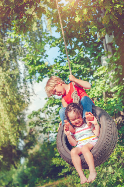 little boy and girl swinging in summer - freedom tire swing tire swing imagens e fotografias de stock