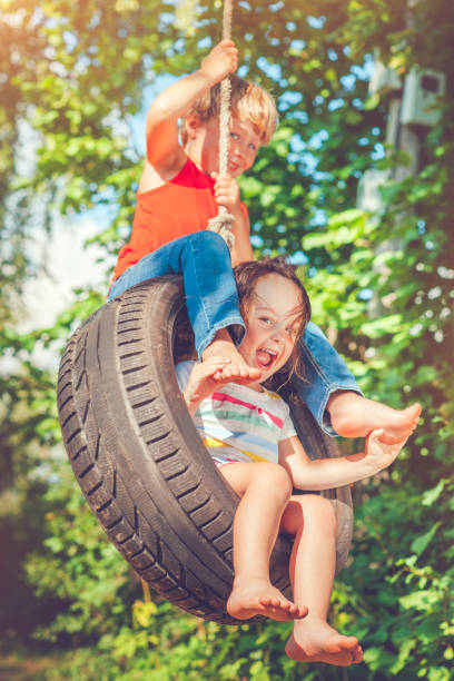 little boy and girl swinging in summer - freedom tire swing tire swing imagens e fotografias de stock
