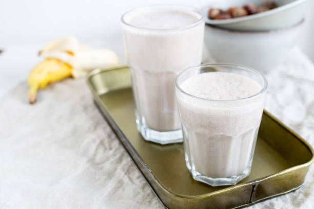 банановый смузи с фундуком. веганская концепция питания - smoothie banana smoothie milk shake banana стоковые фото и изображения