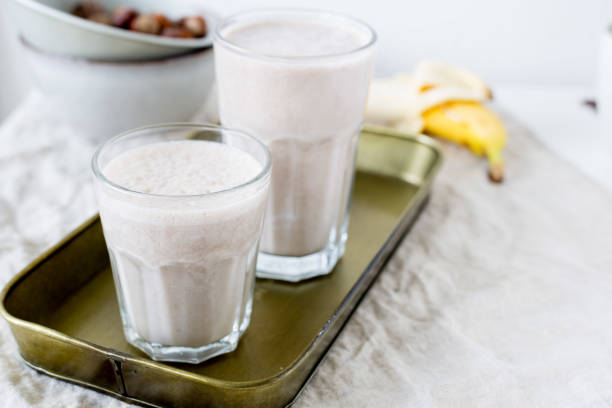 банановый смузи с фундуком. веганская концепция питания - smoothie banana smoothie milk shake banana стоковые фото и изображения