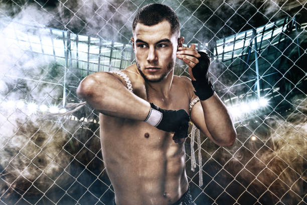 istock Sportsman muay thai boxer fighting in boxing cage. Background with lights and smoke. Copy Space. 668999708