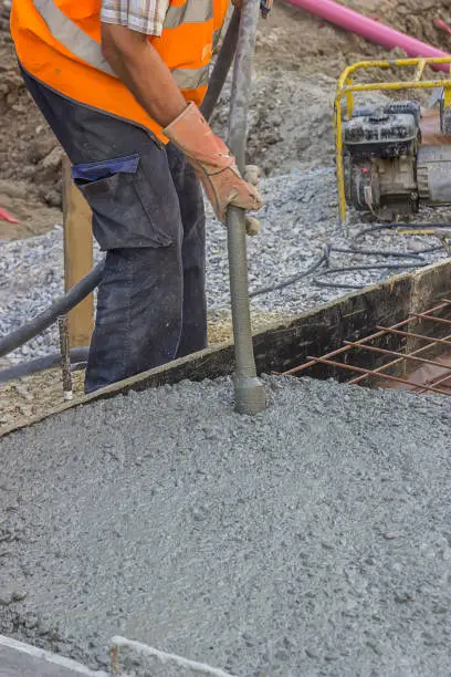 Spreading freshly poured concrete with concrete vibrator for maximum strength and consistency in concrete. Selective focus and shallow dof.