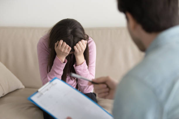 istock Depressed crying woman sitting with her head down, psychologist office 669015834