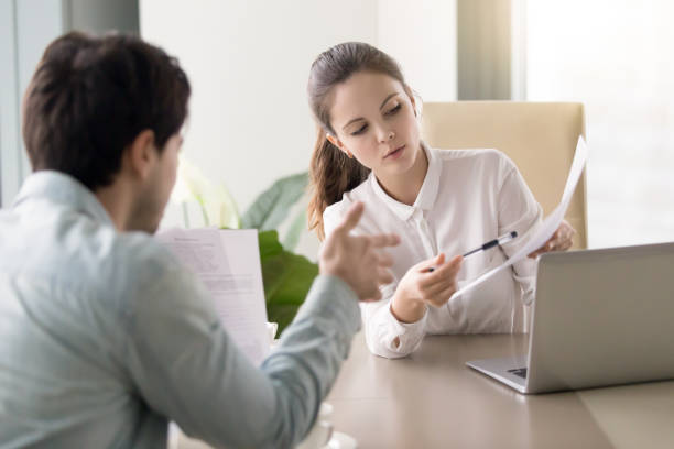 istock Conversation between businesswoman and businessman about documents at office table 669015944