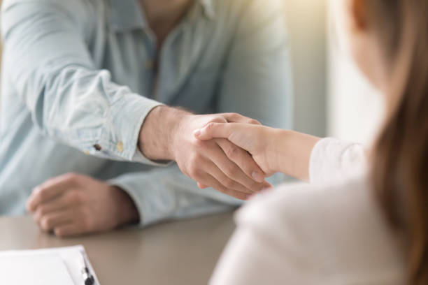 Business agreement handshake of man and woman at the office Businessman shaking female hand above the table. Business agreement and partnership concept. Partners closing a deal, view over the shoulder. Formal greeting gesture, effective negotiations casual handshake stock pictures, royalty-free photos & images