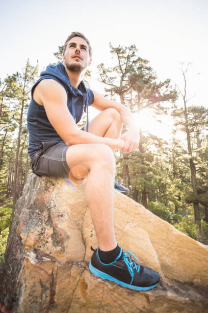 istock Young happy jogger sitting on rock and looking away 669019016