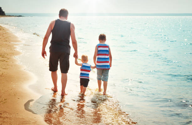 istock Father and sons walking at the beach at sea 669021930