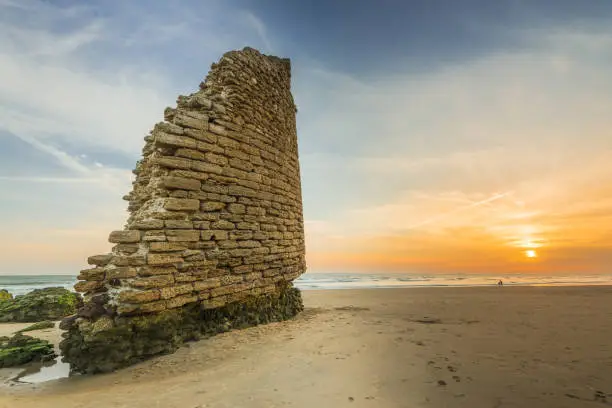 Torre del Loro Roman tower ruins on beach in Mazagon,Spain at beautiful sunset.