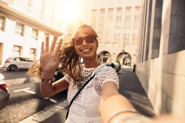 Tourist posing for a selfie in a street. Vlogger recording content for her travel vlog.