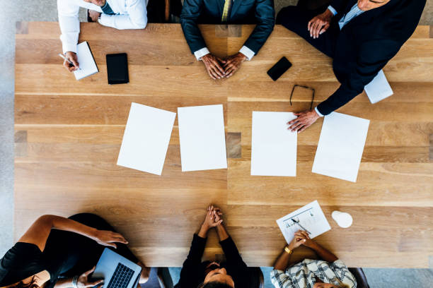 istock Business people sitting around a table with blank sheets 669040486