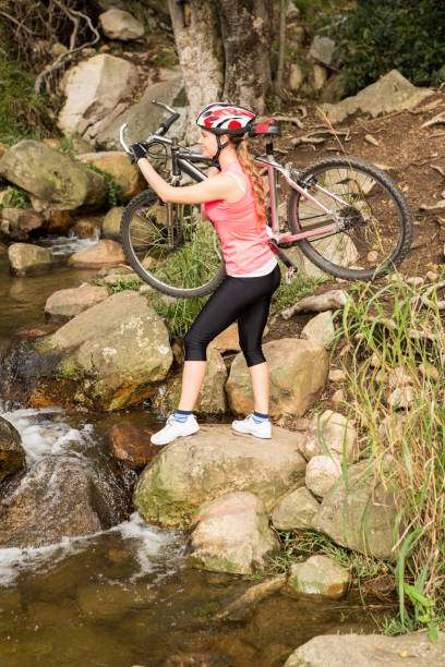 istock Blonde athlete carrying her mountain bike over stream 669080948