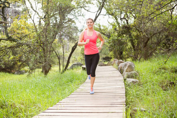blonde athlete jogging on wooden path - running jogging footpath cross country running imagens e fotografias de stock