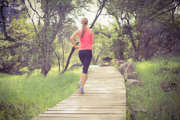 blonde athlete jogging on wooden path - running jogging footpath cross country running imagens e fotografias de stock