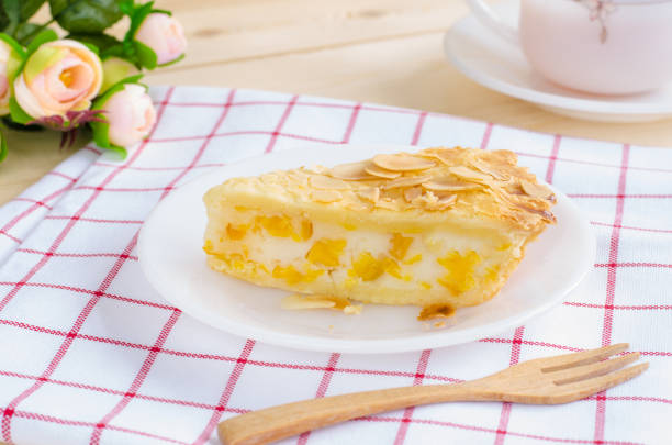 istock Piece of delicious corn pie on white ceramic plate over red & white Scott pattern cloth with black tea in white cup & saucer 669084774