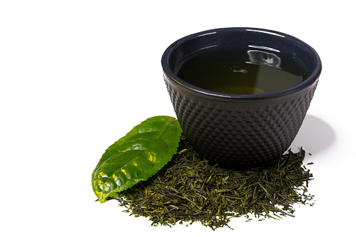 Iron cast cup and heap of green shincha tea, first flush, shadow tea, with leaf, isolated on white background..