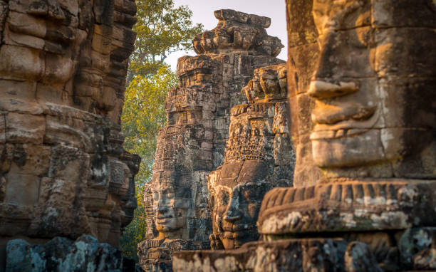 ogromne rzeźbione twarze w ruinach świątyni na zachodzie słońca w kambodży - wat angkor thom zdjęcia i obrazy z banku zdjęć