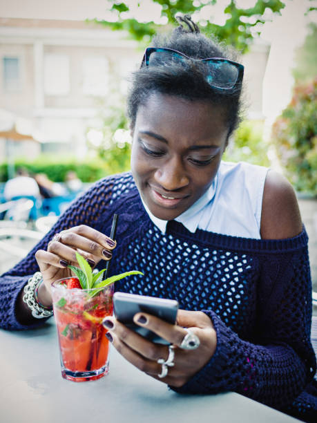 istock Young African Woman text messaging in sidewalk cafe 669088476