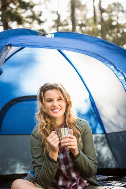 istock Pretty blonde camper smiling and sitting in tent 669091220
