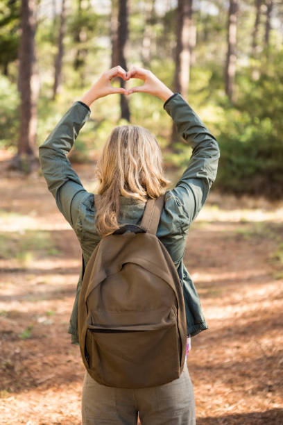 istock Rear view of blonde hiker framing heart with hands 669092420