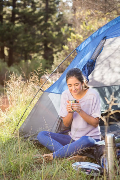 istock Brunette camper enjoying beverage and sitting in tent 669101338