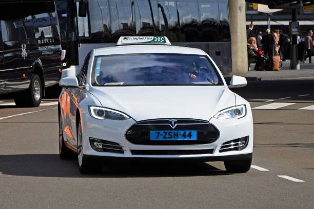 Electric Tesla taxi driving on the street Amsterdam, Netherlands - 11th April, 2017: Electric taxi Tesla S driving on the street. This car debuted in 2013. Tesla S is the most often bought electric car in Norway in 2014, and increasing its popularity in other European countries. The fastest version - Performance S - accelerates from 0 to 60 mph in 4.4 seconds. Tesla Model S have range up to 480 km on a single charge. elon musk stock pictures, royalty-free photos & images