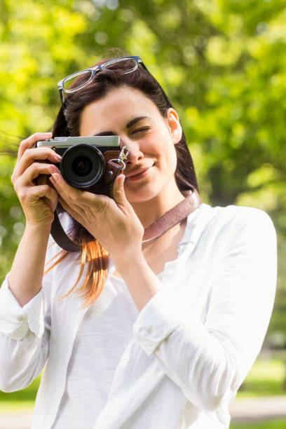 istock Beautiful brunette taking photo in the park 669115910