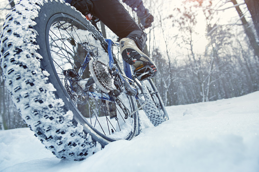 Man rides fat bike in the snow forest. He is wearing unbranded clothes and helmet
