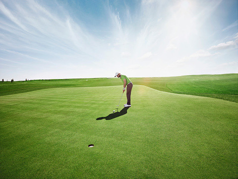 Waist up portrait of smiling man playing golf and swinging golf club against blue sky outdoors, copy space