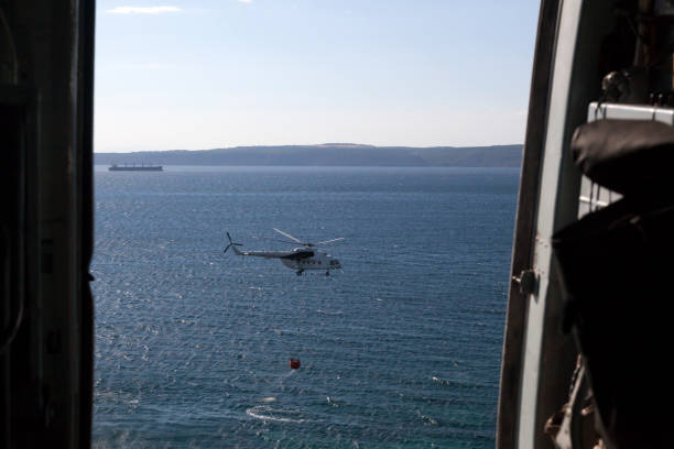 istock Firefighting Helicopter with Water Bucket on Sea 669125646