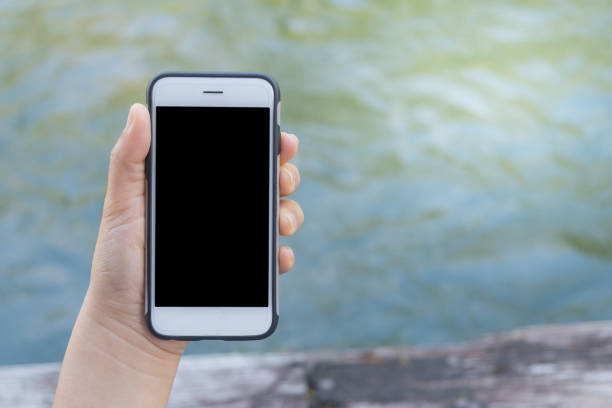 istock Woman with a phone in her hands sitting on pier using smartphone 669161094