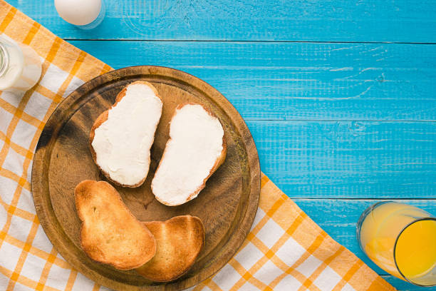 top view of toast bread and toast butter served with juice on wooden table - butter toast bread breakfast imagens e fotografias de stock