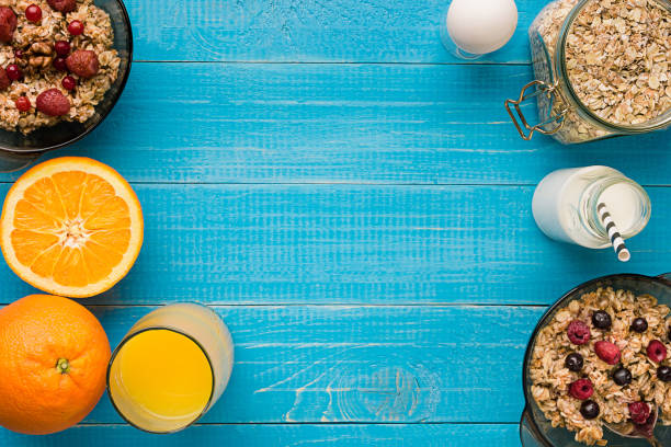 desayuno saludable con tazón de avena casera con jugo de naranja sobre fondo de madera rústica y bayas - oatmeal oat box container fotografías e imágenes de stock