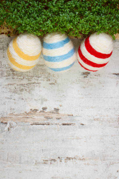 oeufs de pâques enveloppés chaîne de laine et cresson vert sur fond en bois, espace de copie pour le texte, décoration pour pâques - easter bonnets photos photos et images de collection